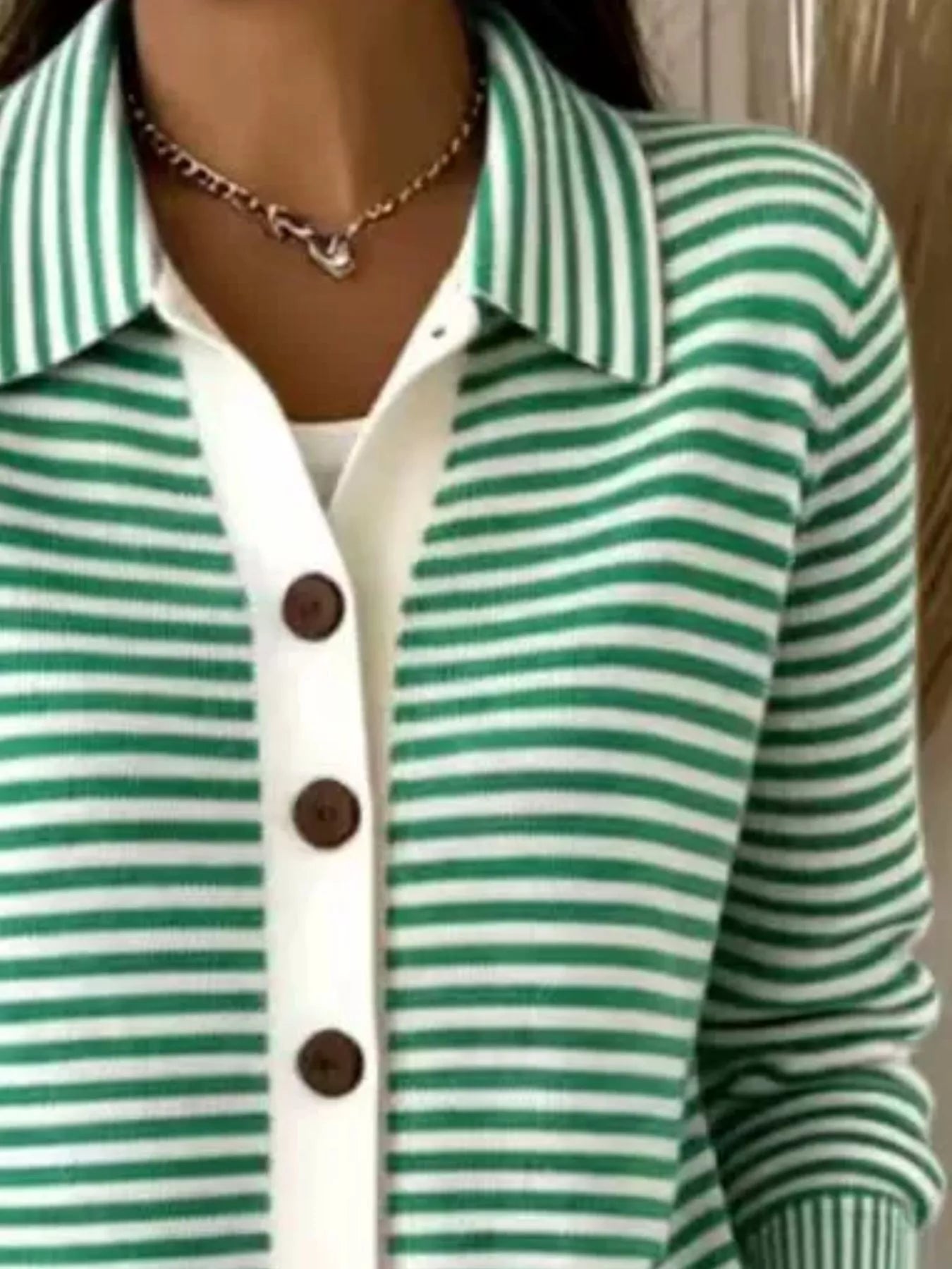 Close-up on-model view of green and white striped collared cardigan with brown buttons