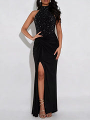 Black sleeveless maxi dress with rhinestone halter bodice twisted waist and front slit on model