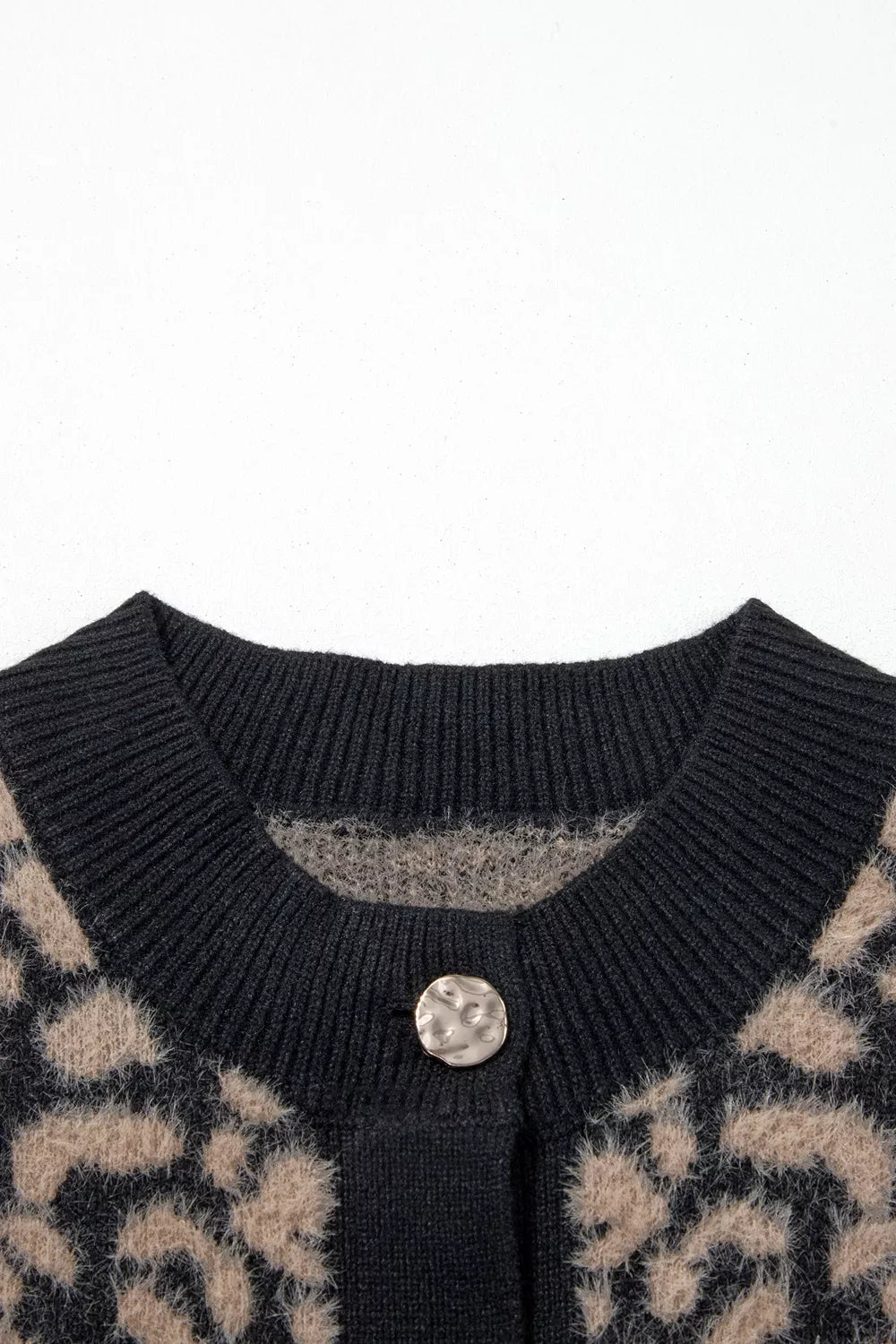 Close up of black ribbed neckline and gold button on leopard print vest.