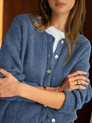 Close up of haze blue button down cardigan with white buttons worn over a white top