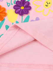 Close-up of pink children's t-shirt hem stitching with purple flower applique and printed flowers above