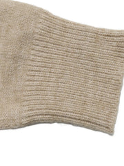 Close-up of the beige ribbed sleeve cuff on the argyle polo sweater