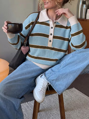 Seated front view of blue and brown striped polo sweater worn with light jeans.