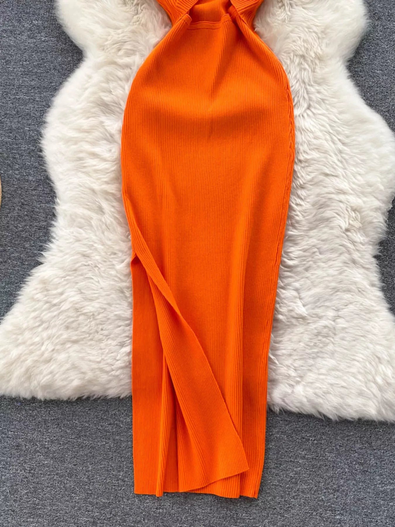 Lower skirt of orange ribbed knit midi dress showing side slit detail