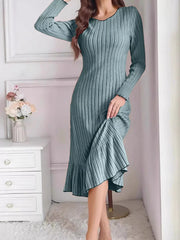 Turquoise ribbed knit bodycon dress with ruffle hem worn indoors, front view lifting the skirt