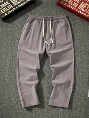 Men's light gray loose-fit pants with a drawstring waist and pockets.