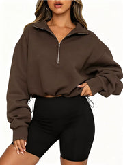 Front angled view of brown half zip sweatshirt with hand at waist and drawstring hem