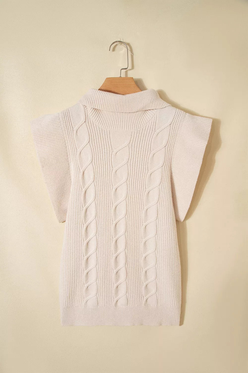 Hanging back view of a cream cable knit turtleneck sweater with ruffled short sleeves
