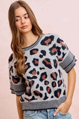 Side front view of a light gray leopard print knit top with striped trim.