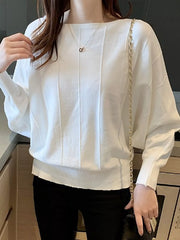 Close front view of the white batwing sleeve knit top with vertical seams, worn indoors with a chain bag.
