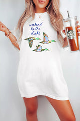 White oversized T-shirt featuring “Weekend by the Lake” text and colorful flying duck graphics, worn by a model