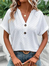 White eyelet short-sleeve top with notched neckline, button front, and rolled cuffs.