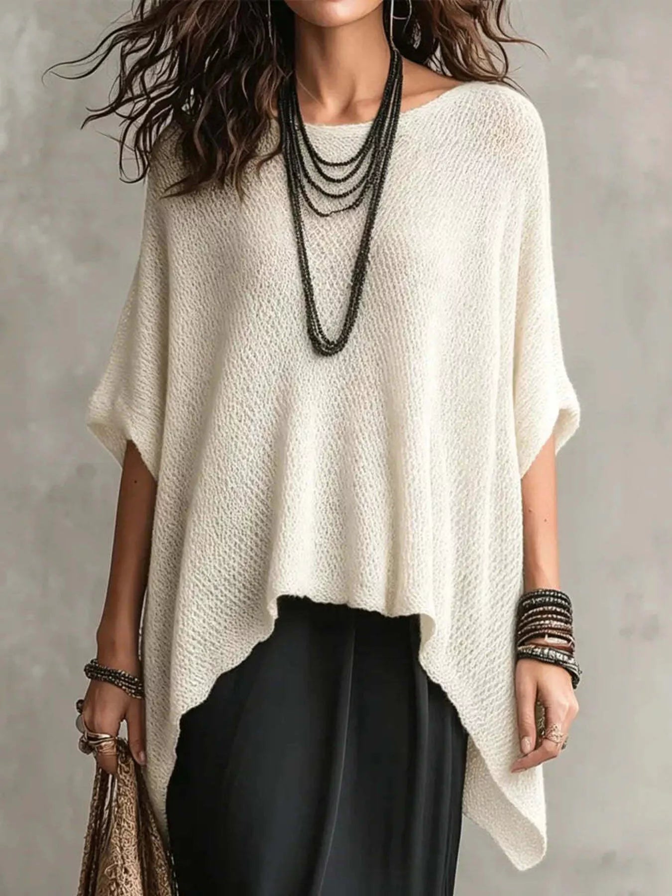 Front view of a loose white open knit cover-up with an asymmetrical pointed hem