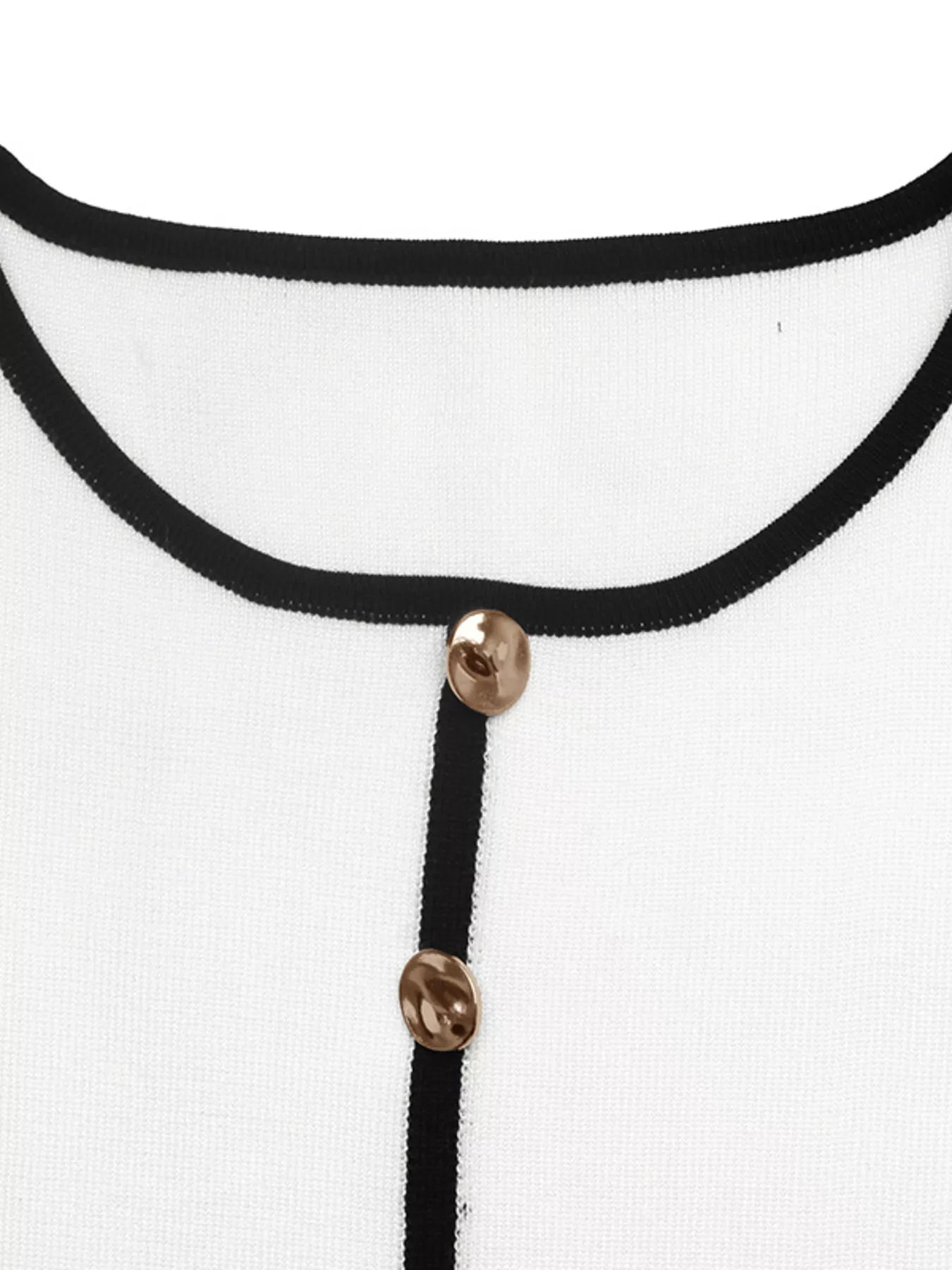 Close up of white knit top neckline with black trim and large gold buttons.