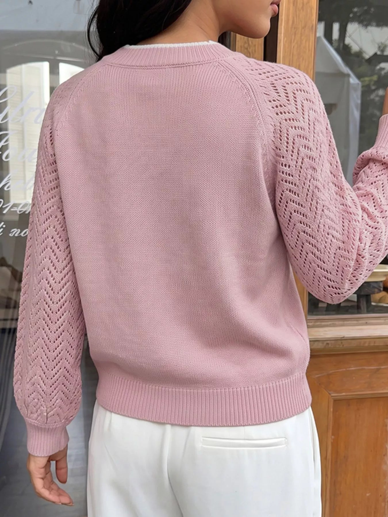 Back view of a pink V neck sweater with plain body and openwork chevron long sleeves.