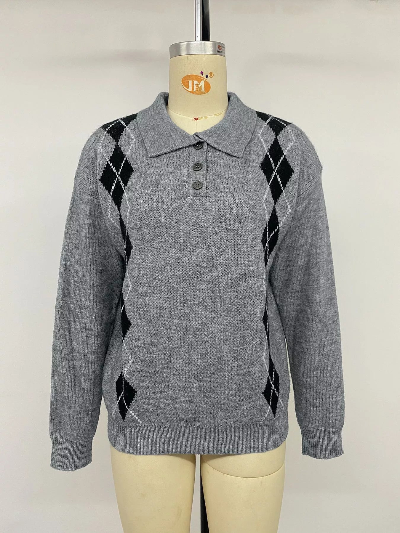 Front view of a gray argyle polo sweater with three buttons on a mannequin