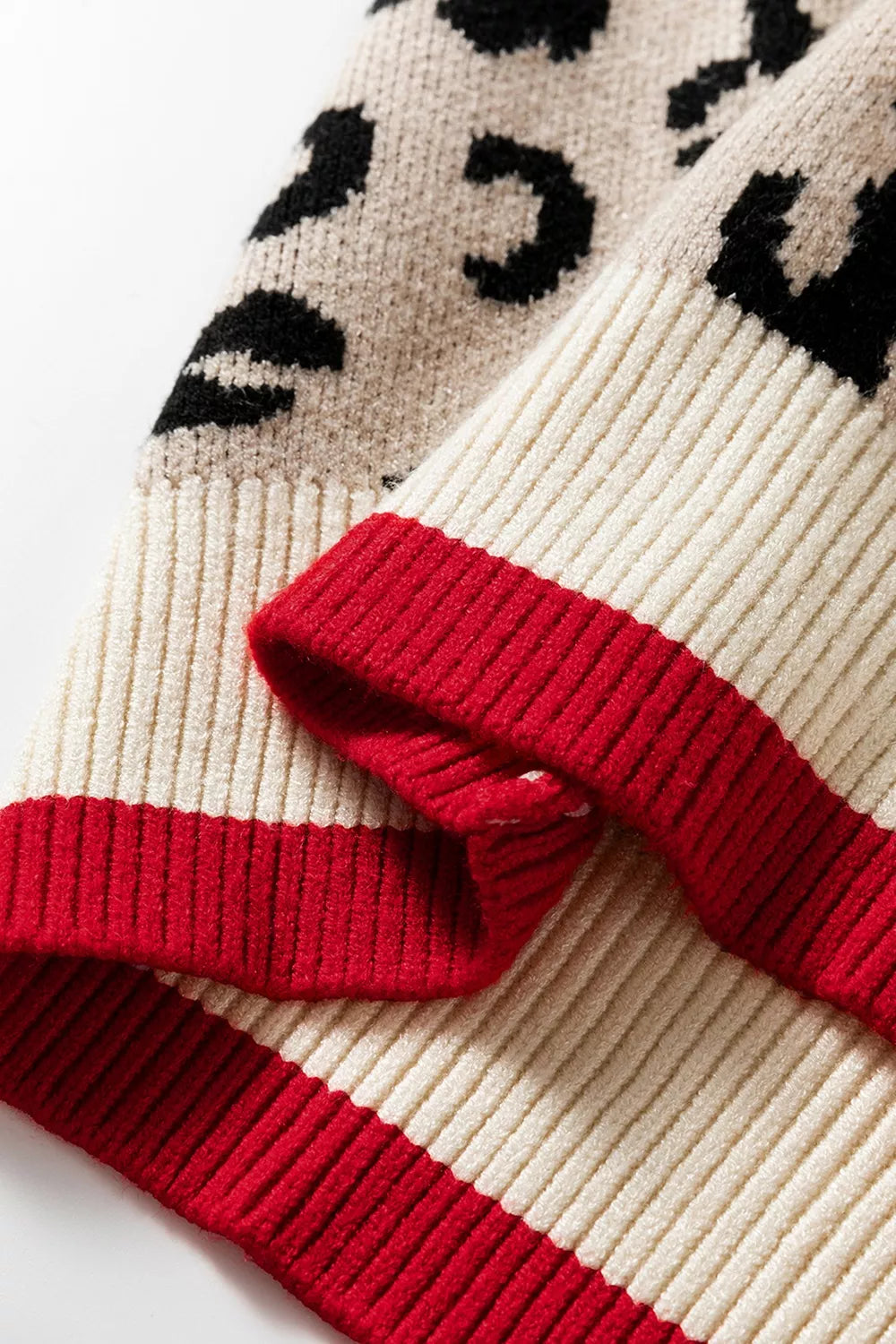 Close view of cream and red ribbed hem and cuff on a leopard print sweater.