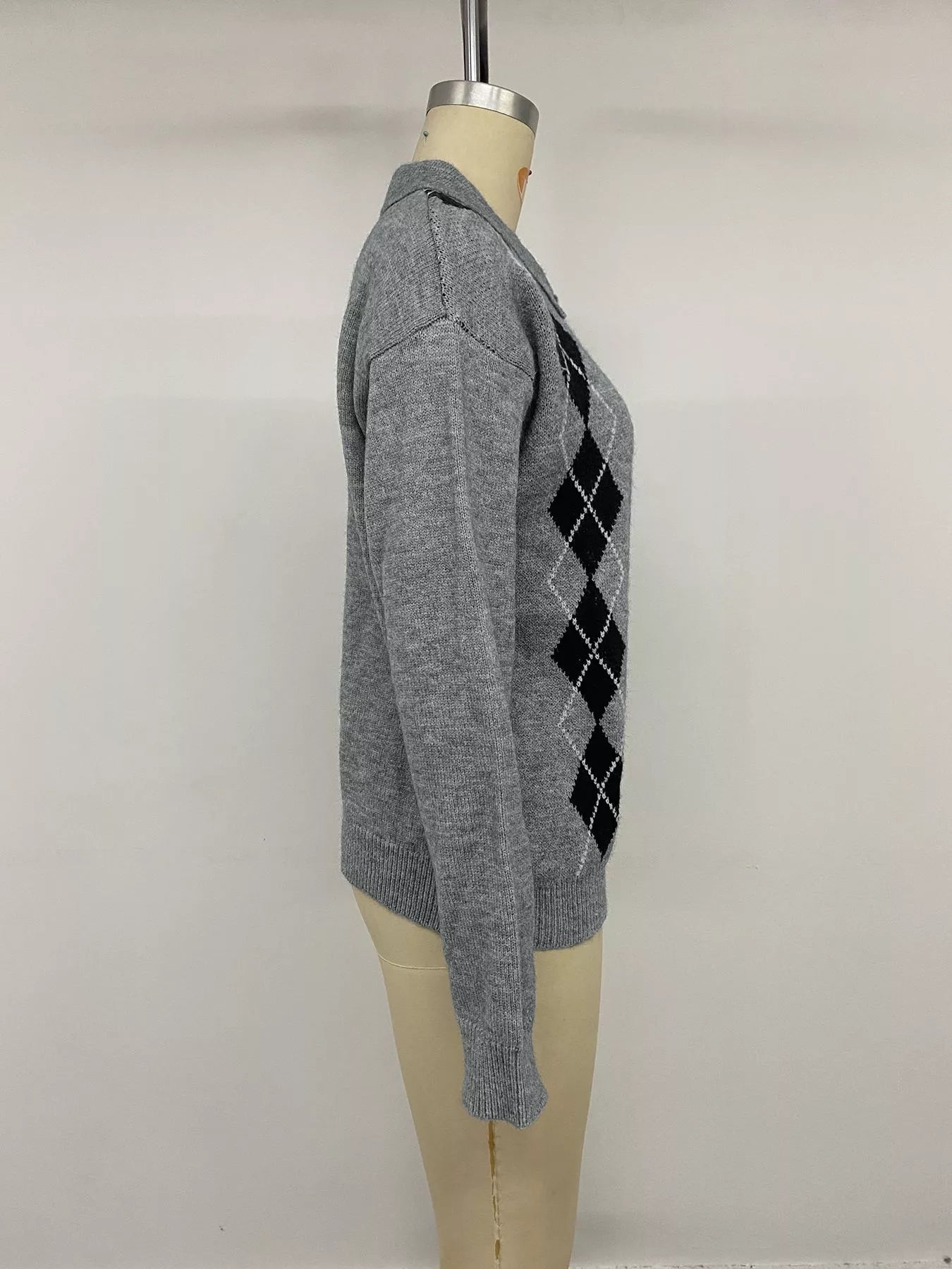 Side view of a gray argyle polo sweater with black diamond panels on a mannequin