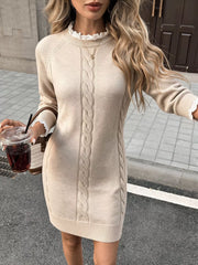 Beige cable knit sweater dress with lace trimmed collar, shown on model outdoors holding a drink