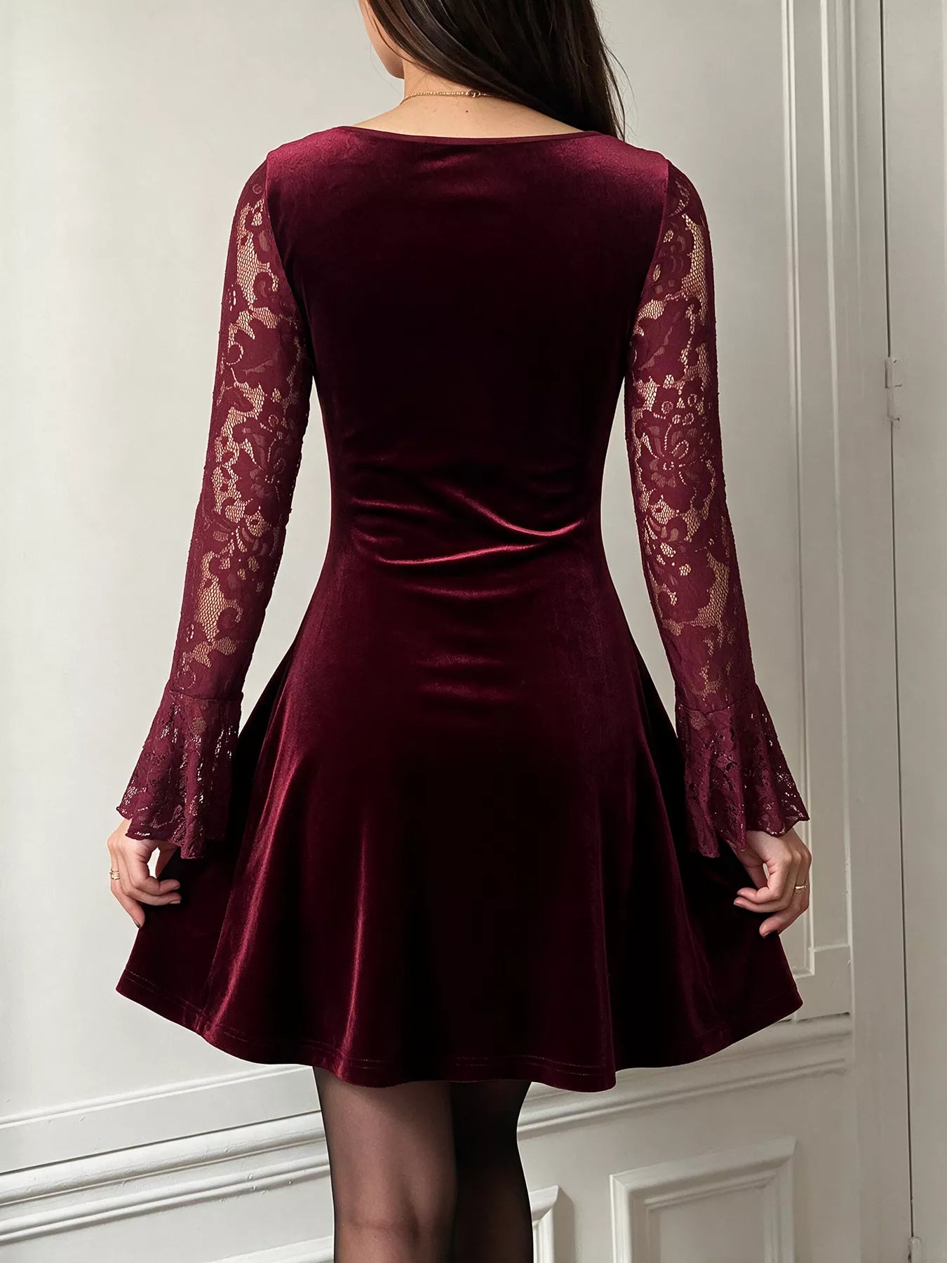 Back view of burgundy lace mini dress with velvet skirt and flared lace sleeves