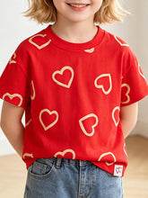 Front view of a red children's tee with cream heart outlines, worn on a model