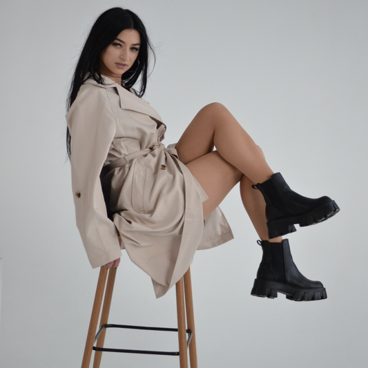 a person in a trench coat sitting on a chair