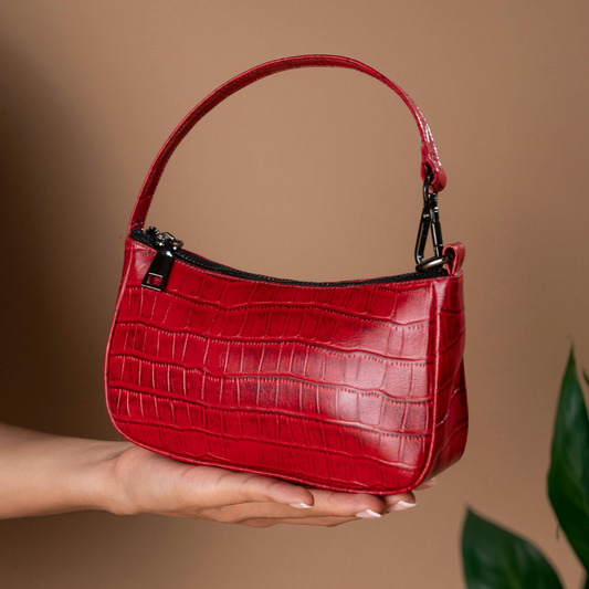 a person holding a red crocodile skin handbag