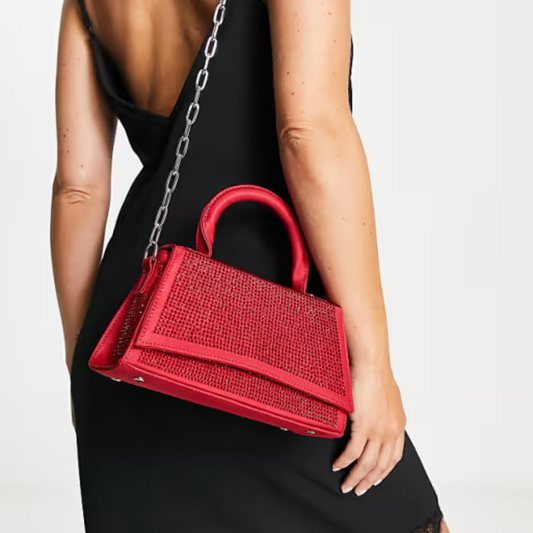 A person in a black dress holding a red handbag