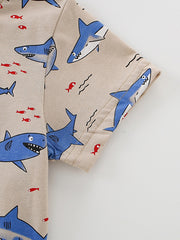 Detail view of a short sleeve and hem stitching on a children's beige shark print t-shirt