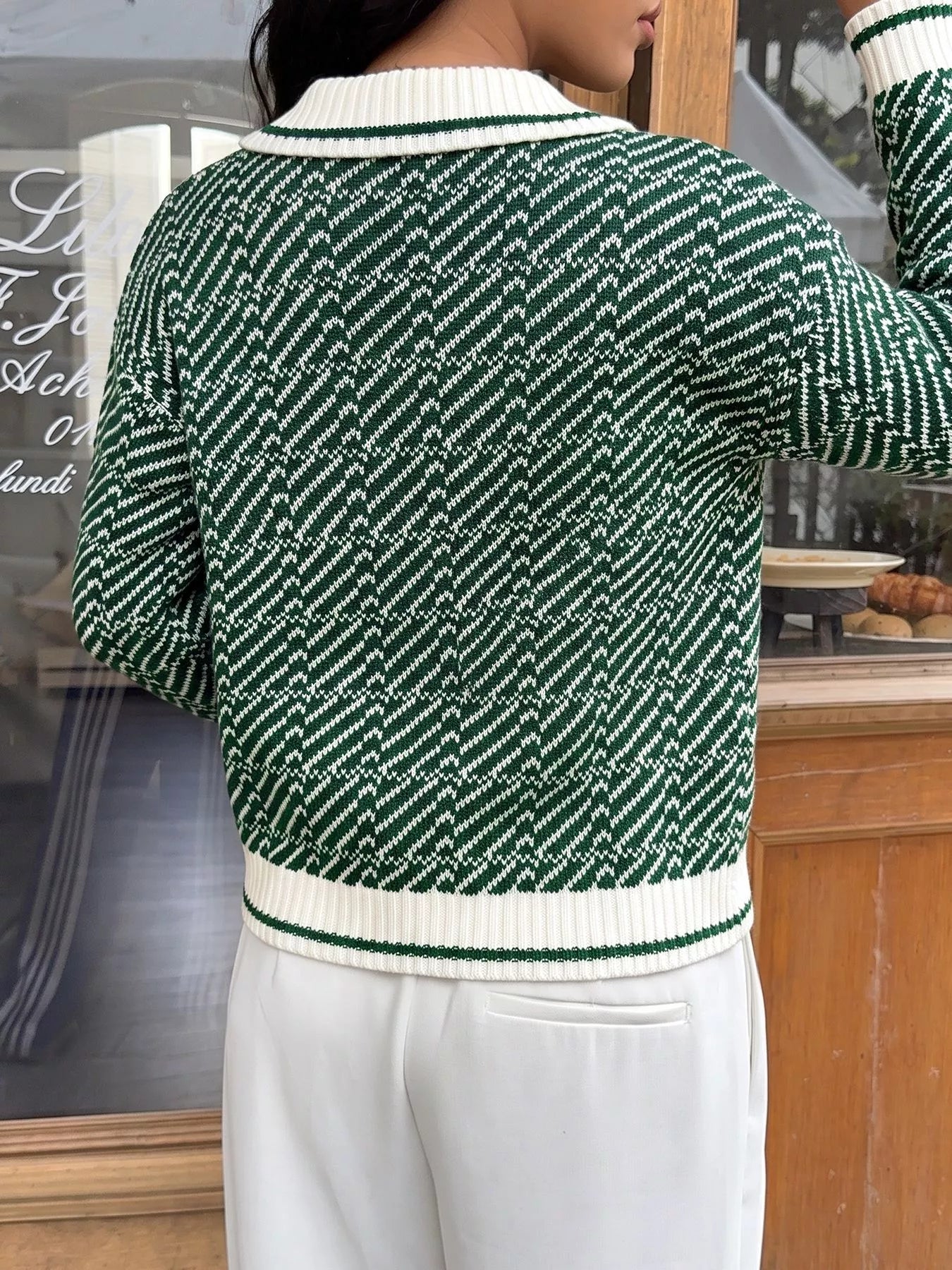 On-model back view of the green and white geometric patterned collared sweater