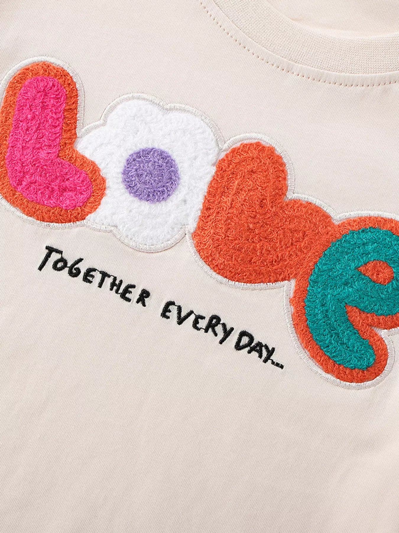 Close-up detail of the colorful textured LOVE lettering with flower heart and together every day text