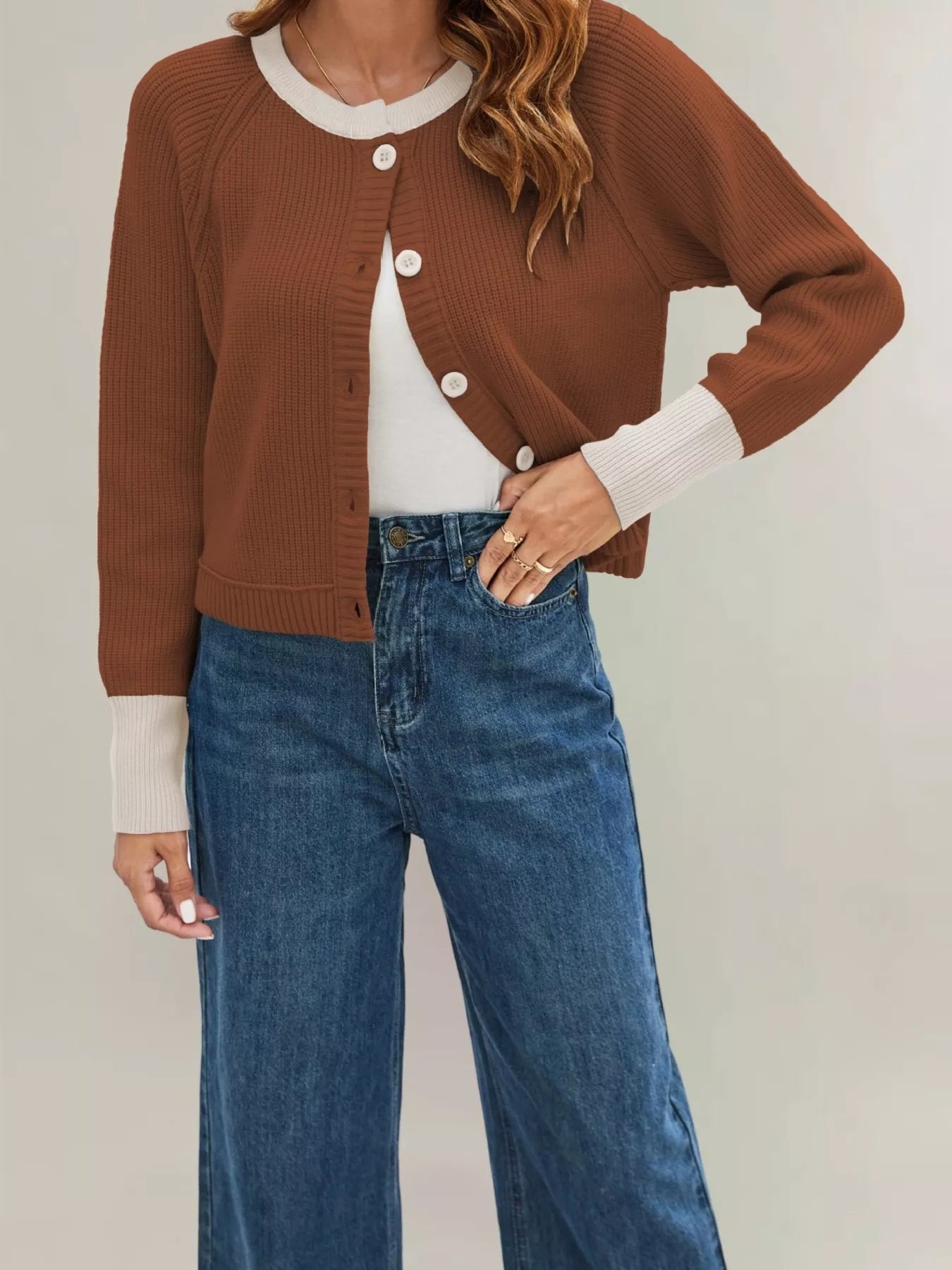 On-model front view of a rust brown ribbed cardigan with cream trim and white buttons