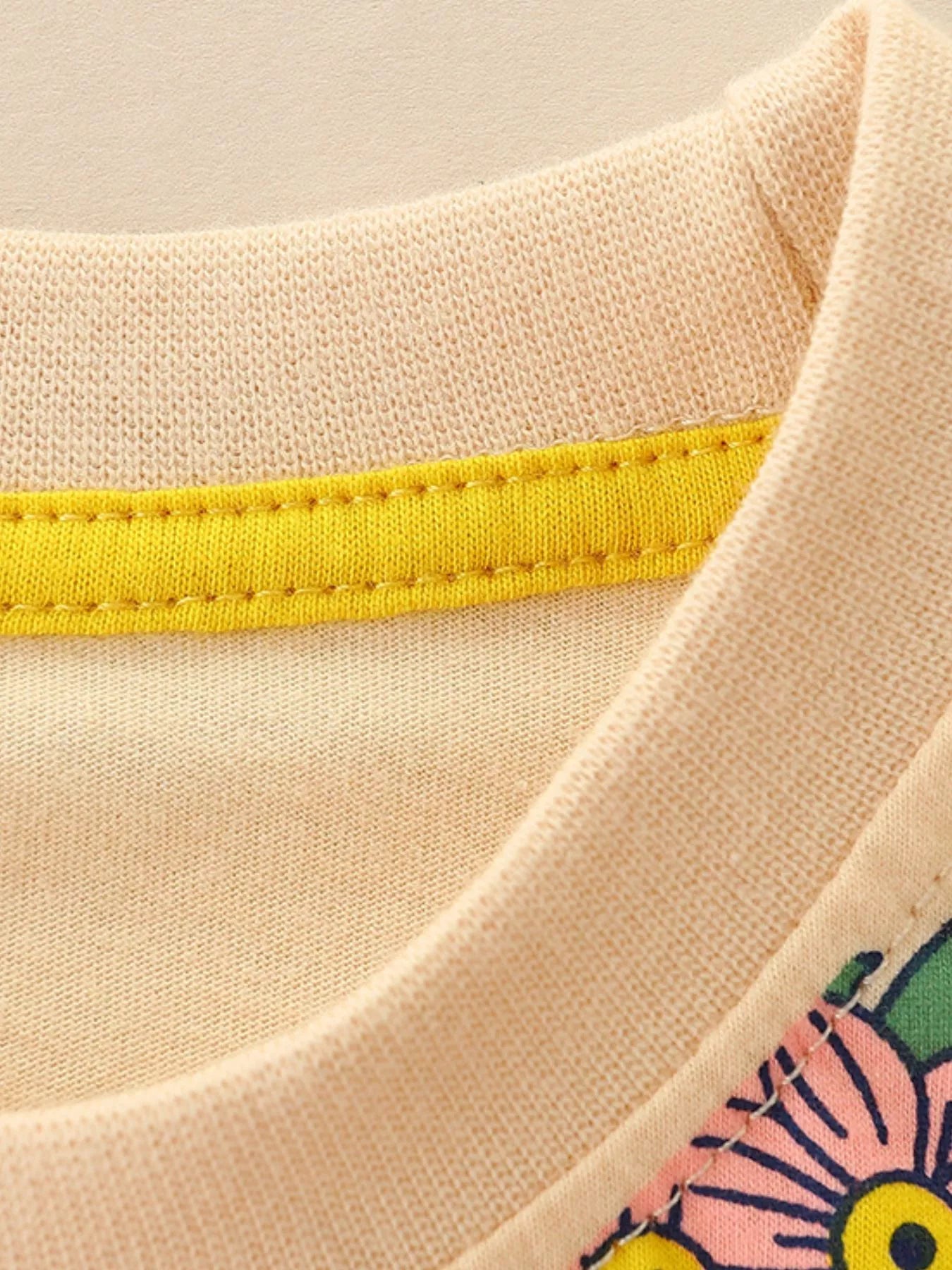 Close up of the round neckline with yellow inner trim on a cream children's guitar tee