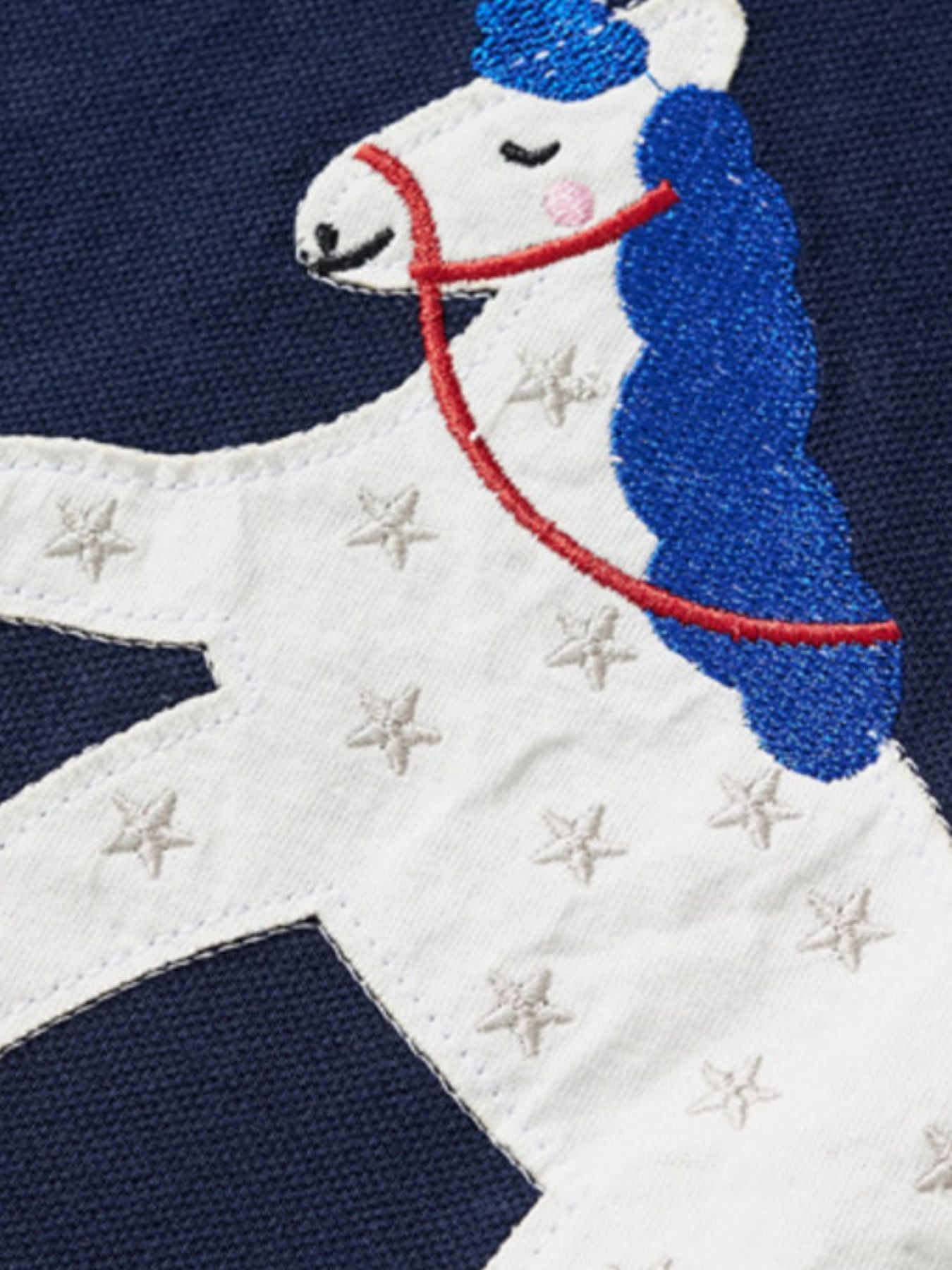 Close-up detail of the white unicorn appliqué with blue mane and embroidered stars