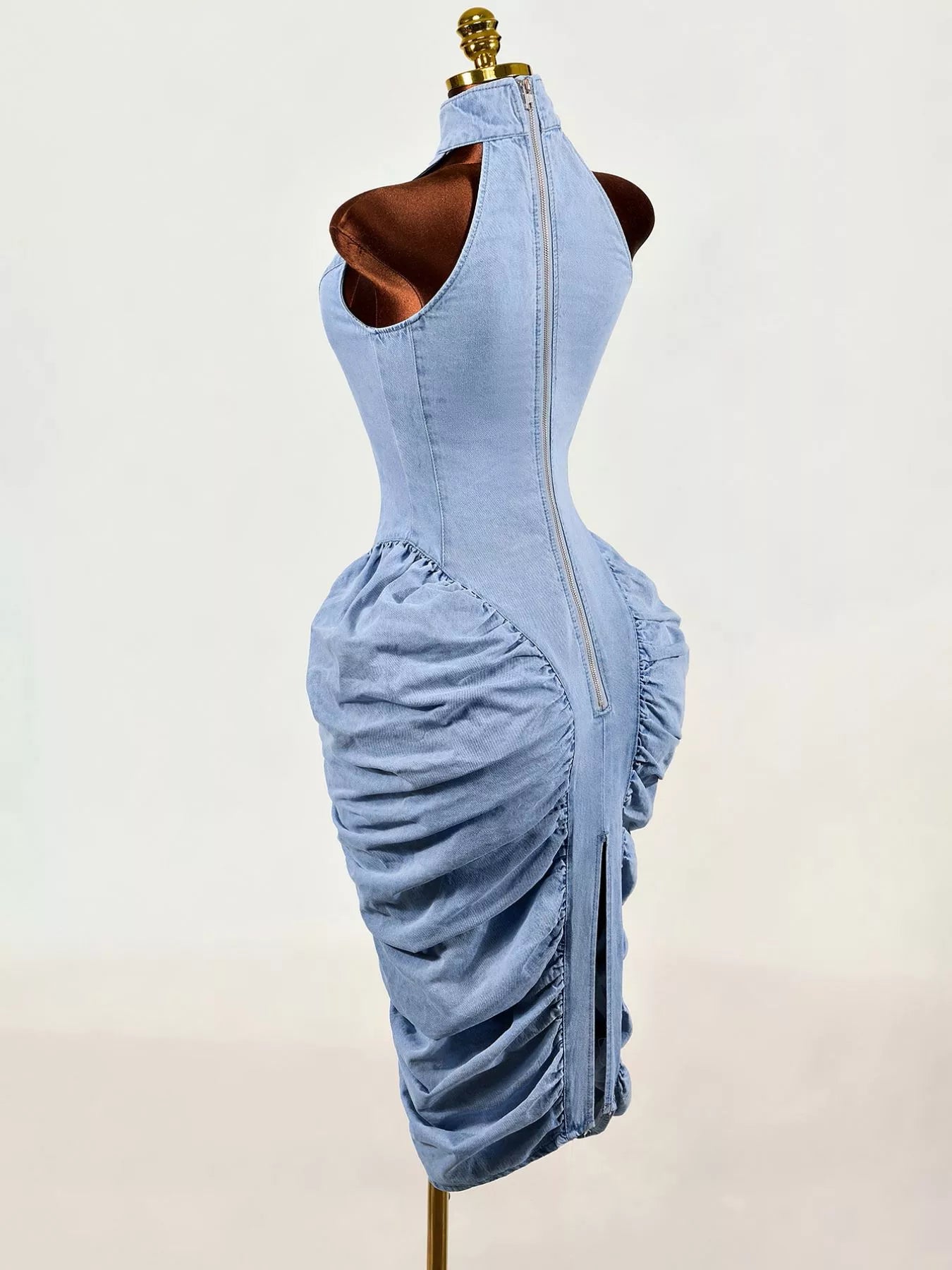 Light blue sleeveless mock neck ruched bodycon denim dress on mannequin, back side view with zip