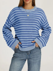 Front view of a light and dark blue striped dropped shoulder sweater with ribbed cuffs worn with jeans.