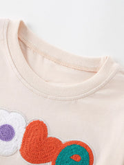 Close-up of the round neckline with neat stitching above the colorful textured LOVE applique