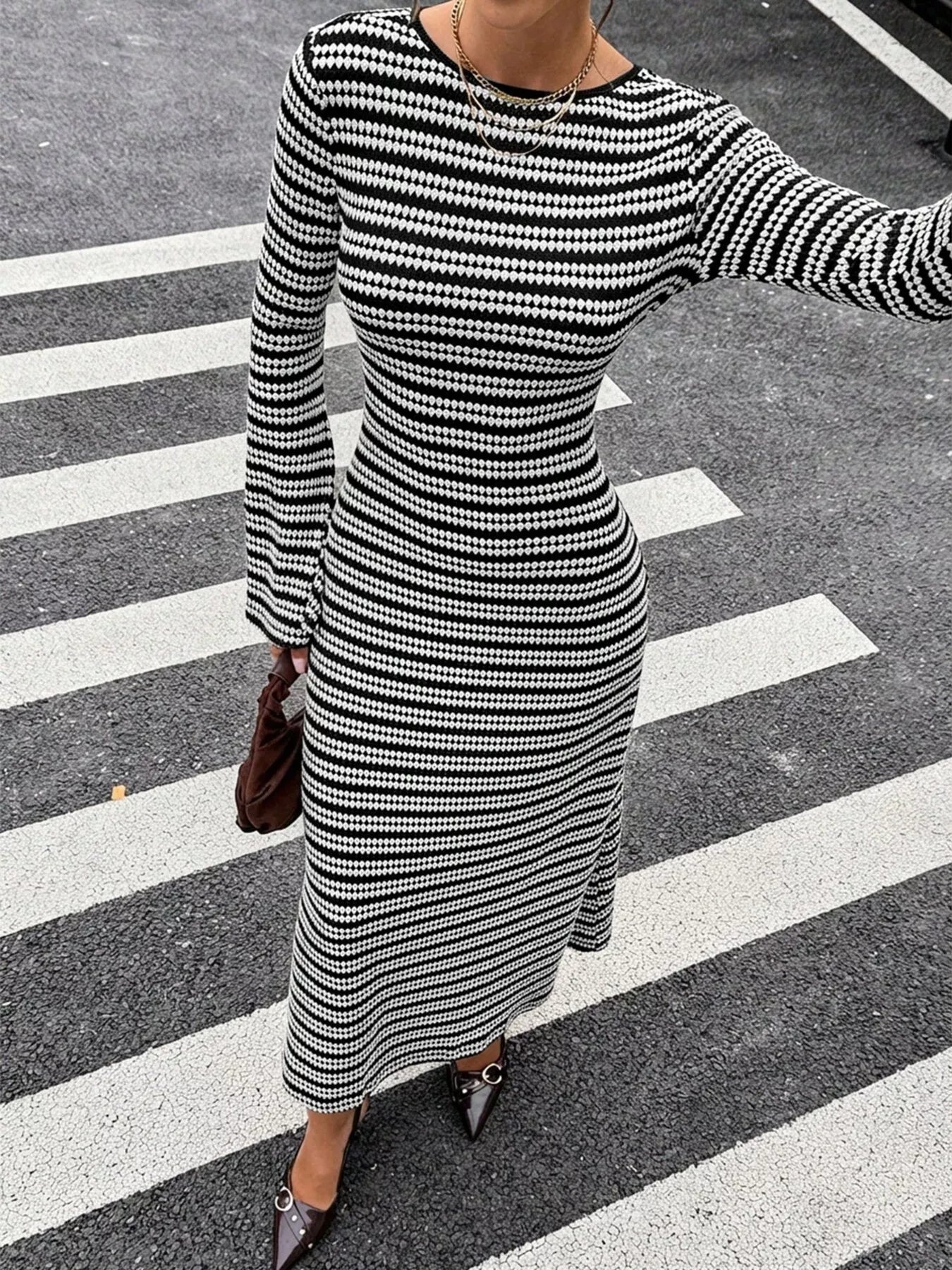 On-model front view of the black and white striped sweater dress with one arm extended