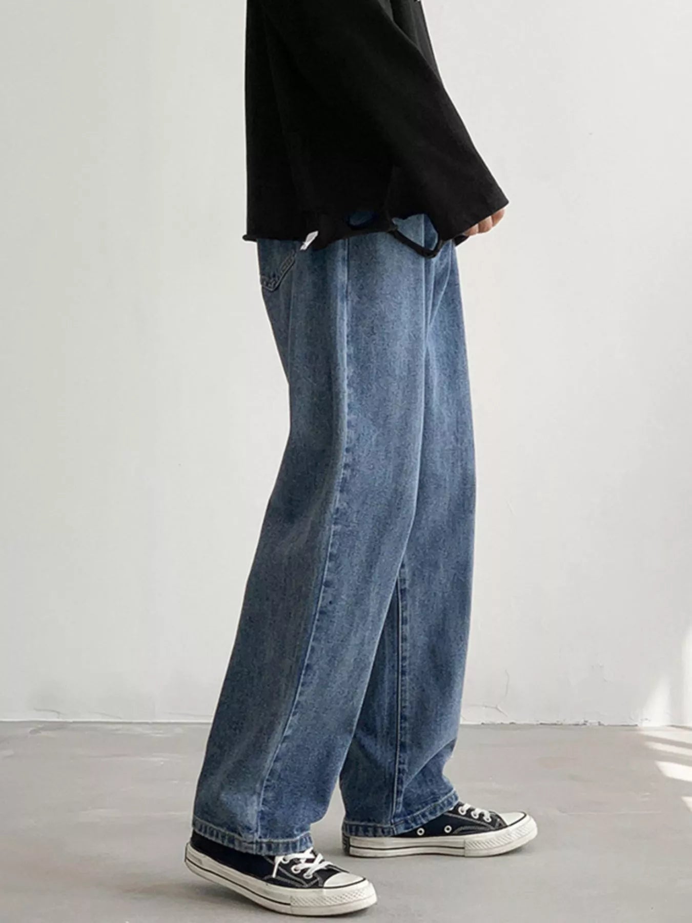 Men's Light Blue loose fit wash jeans on model, side view showing straight legs.