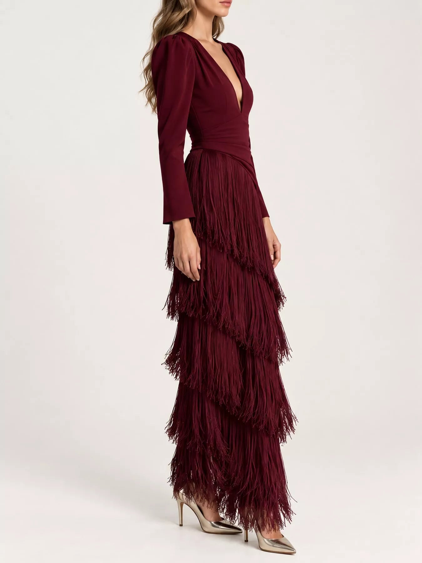 Studio side view of a burgundy fringed maxi dress with tiered fringe layers