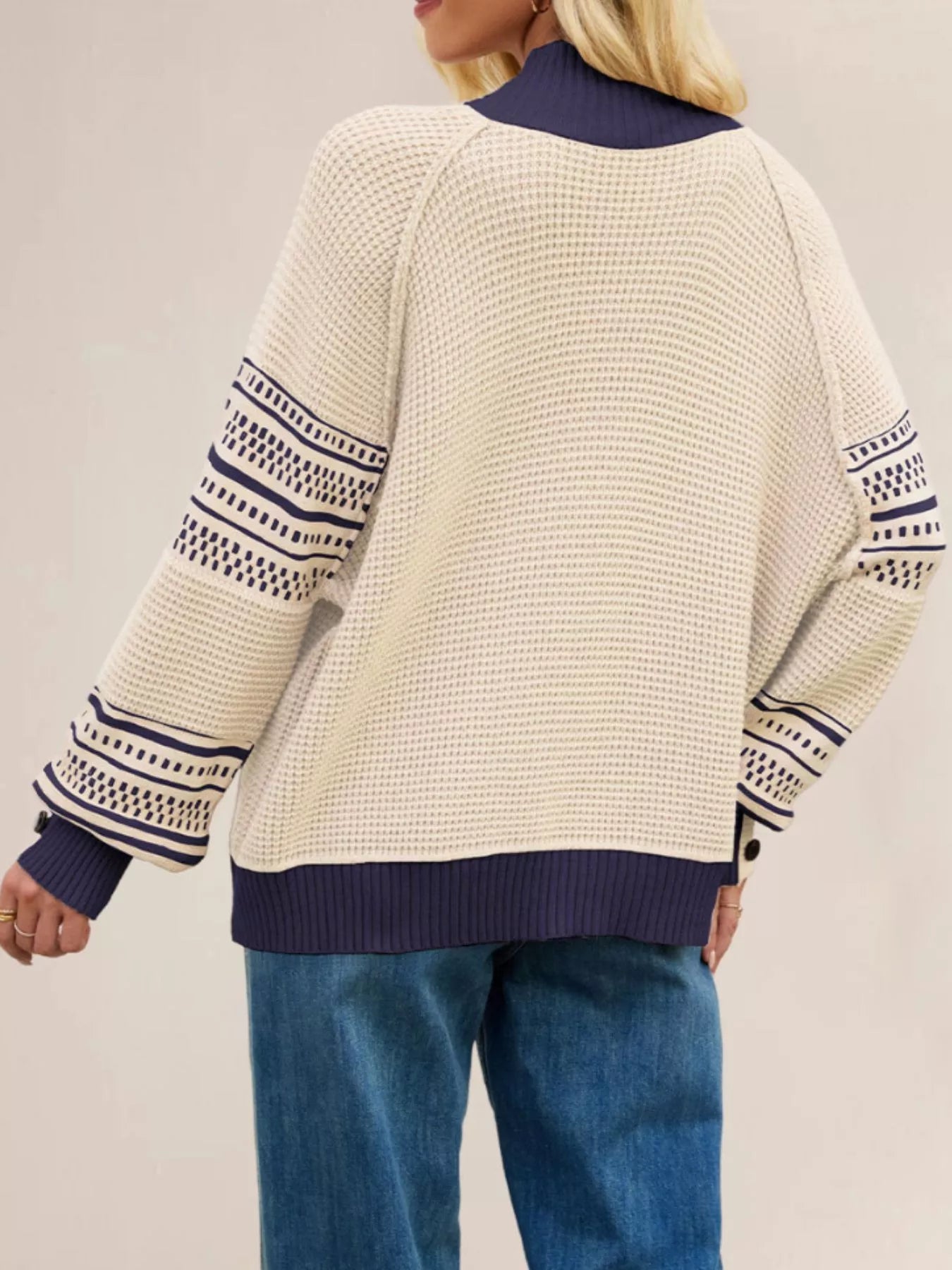 Back view of the cream waffle knit sweater with navy mock neck and patterned sleeves.