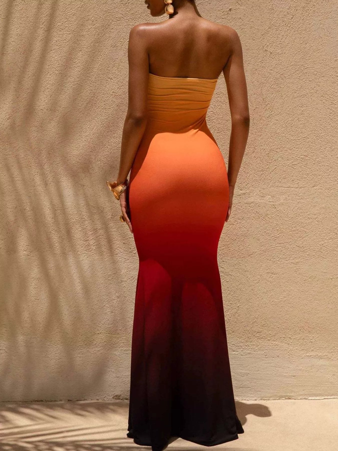 Model wearing strapless gradient orange red and black tube maxi dress, back view