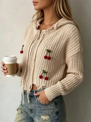 Side view of apricot knit zip up hooded sweater with red cherry appliques and frayed hem