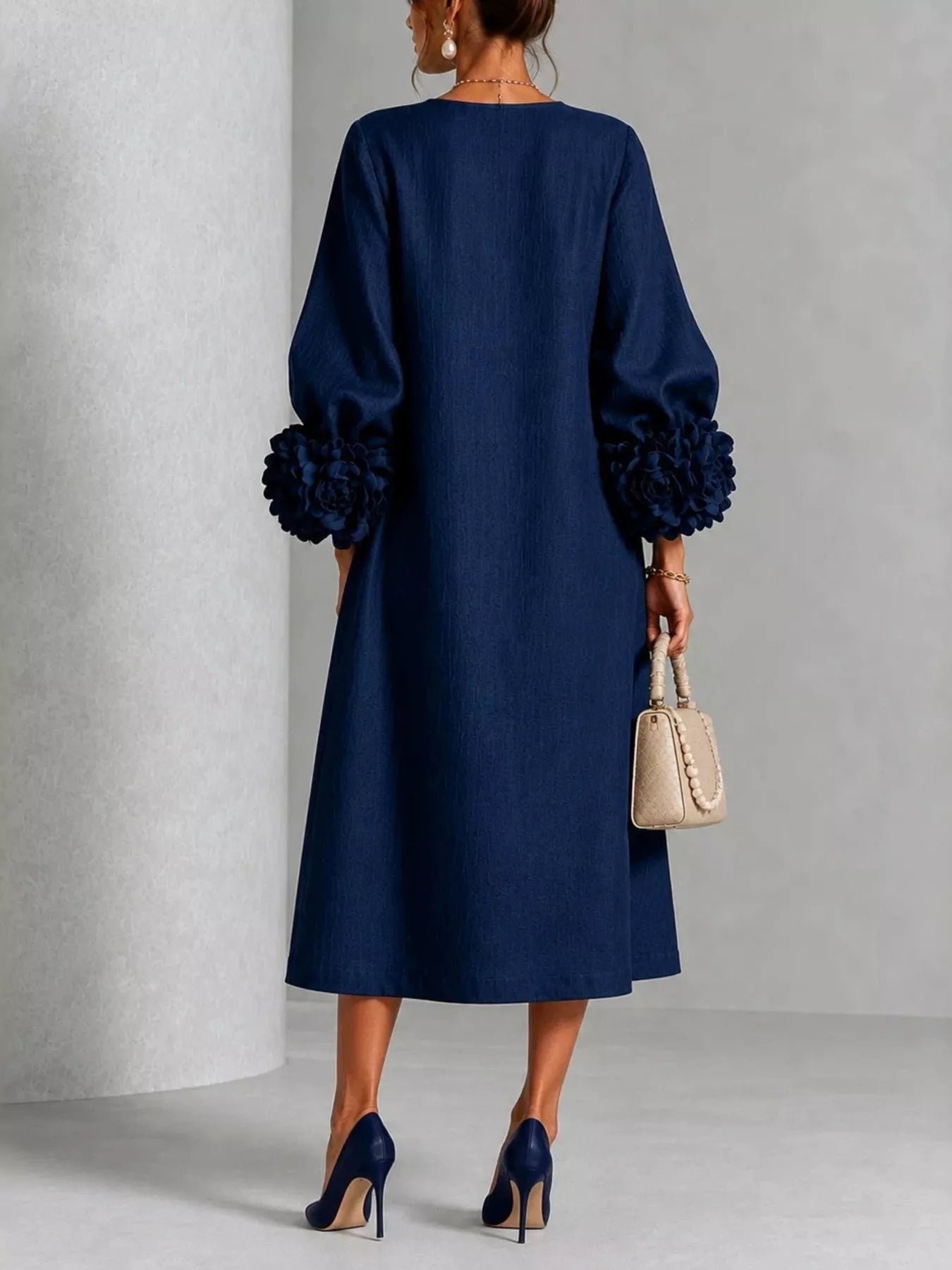 Back view of the navy round neck midi dress with balloon sleeves and large floral sleeve cuffs