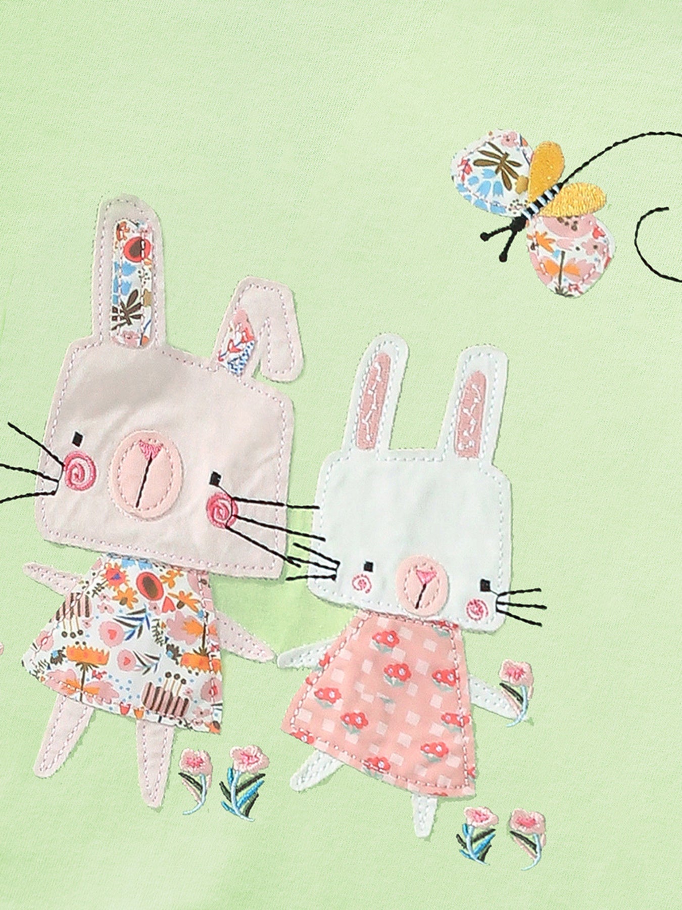 Close-up detail showing the two bunny appliqués and butterfly on light green children's tee