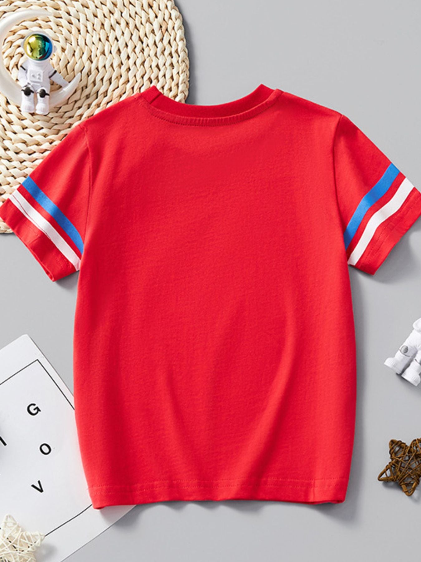 Back view of plain red children's T-shirt with blue and white striped sleeves laid flat