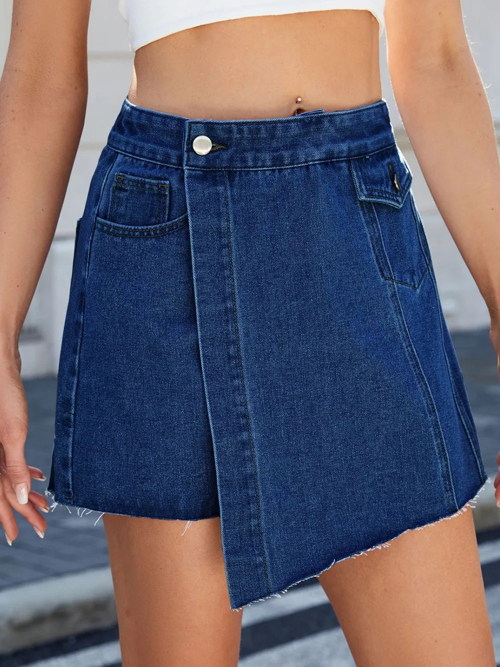 Women's denim skort with an asymmetrical shape and frayed hem.