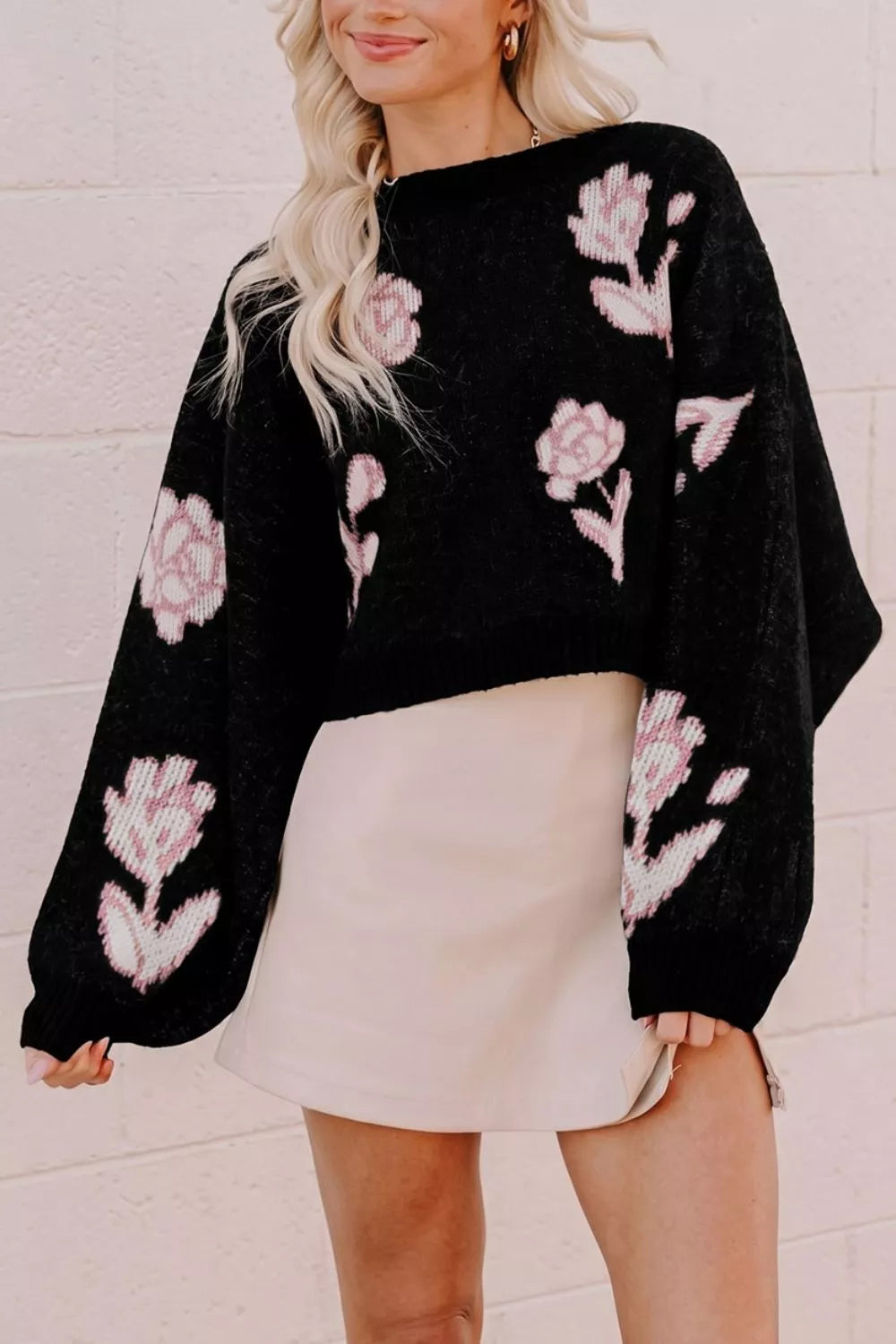 Front view of black floral pullover sweater with pink roses and wide puff sleeves indoors