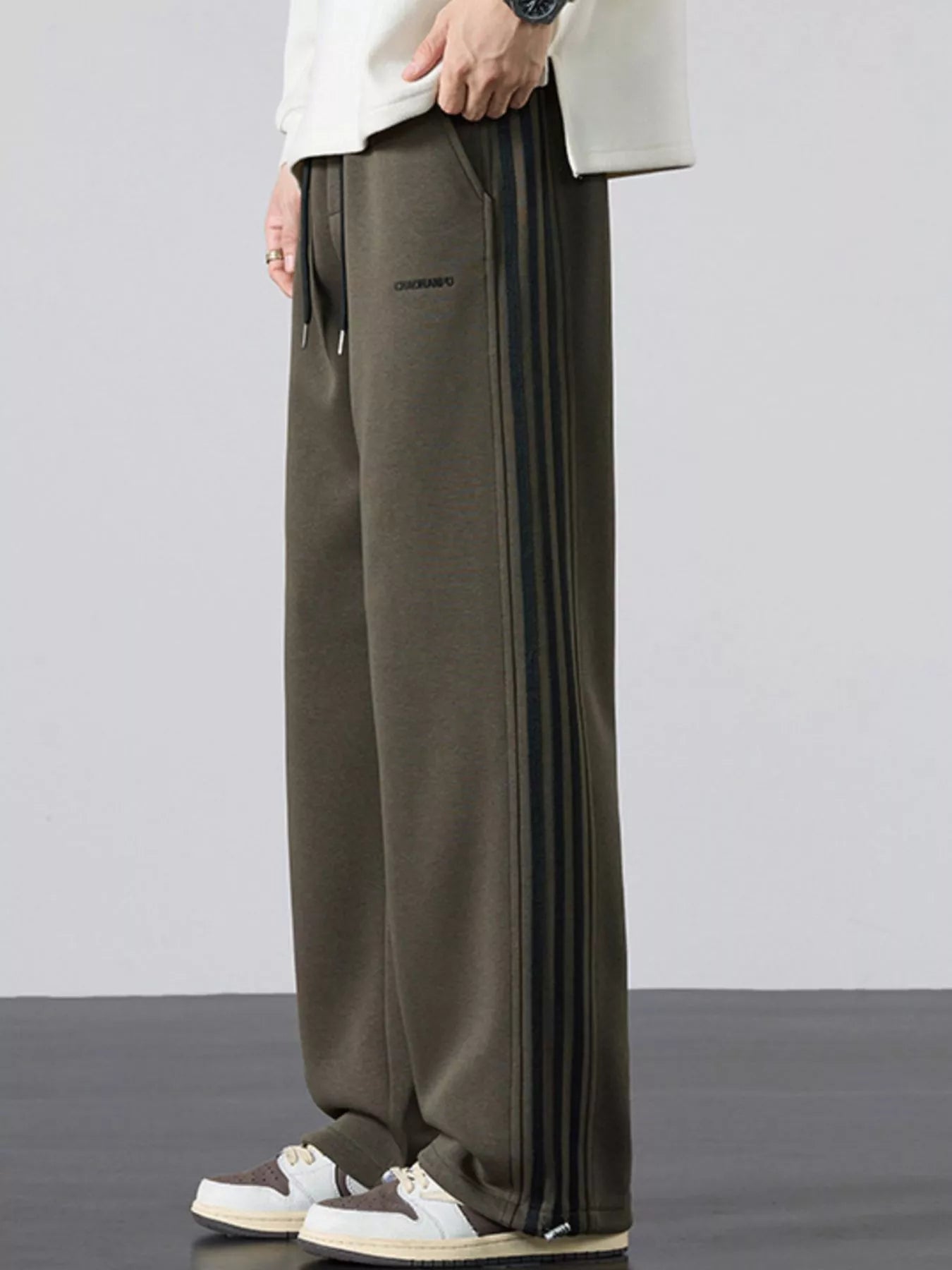 Men's army green striped wide-leg sweatpants with a drawstring waist and pockets.