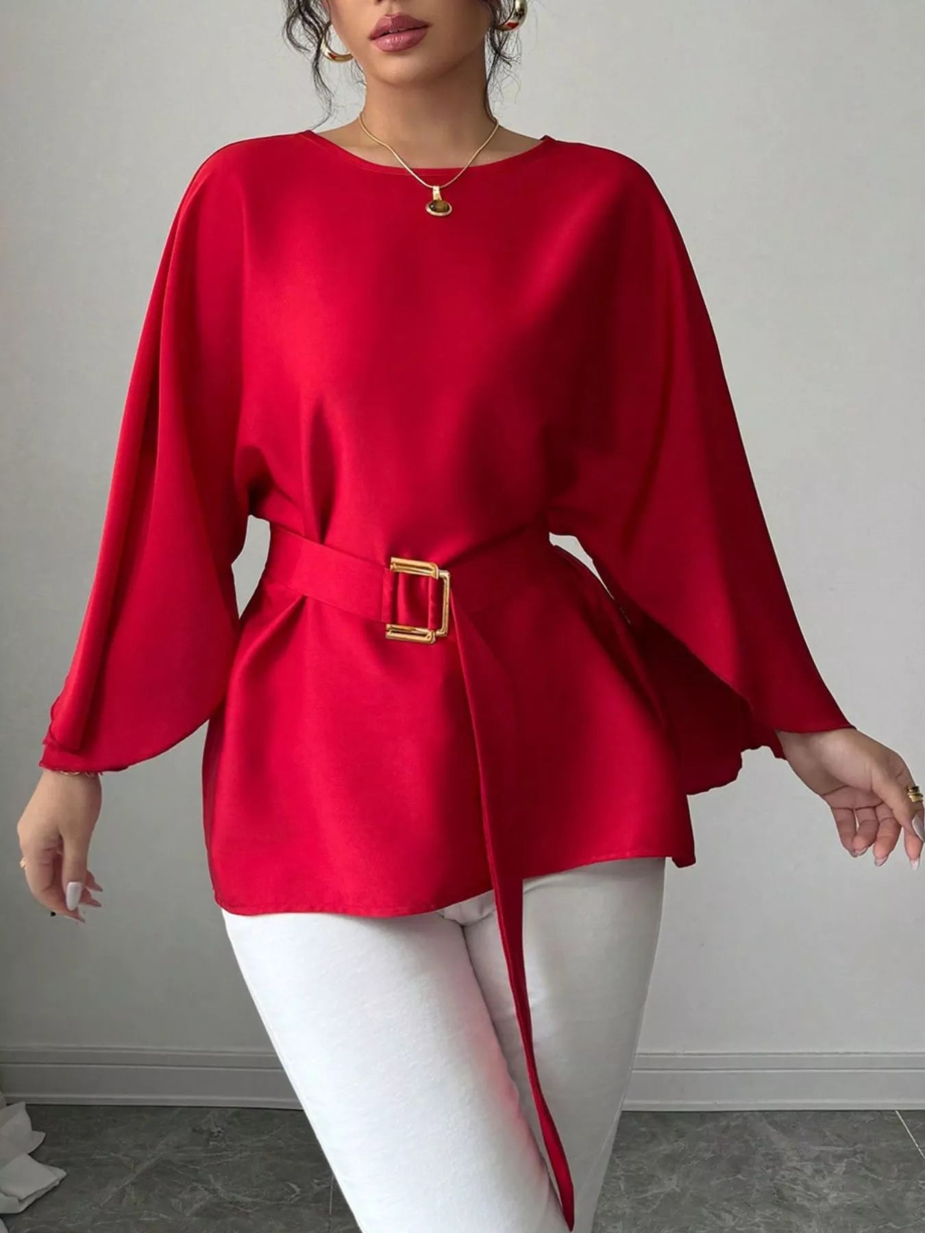 Red batwing sleeve blouse front view with arms extended showing flowing sleeves and belted waist
